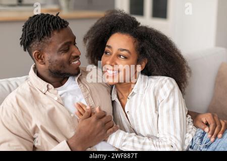 Loving Black Young Couple Embracing Smiling To Each Other Indoor Stock Photo