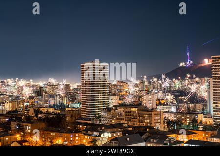 A vibrant display of fireworks bursting over the night sky of Tbilisi, lighting up the cityscape with various colors and patterns Stock Photo