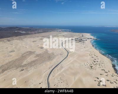 Top view of expansive view of a road meandering through Corralejo Dunes against a backdrop of ocean and clear skies in Fuerteventura Stock Photo
