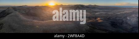 Panoramic sunset view over the volcanic ridges of Fuerteventura's barren landscape, extending from El Cotillo to Majanicho with the Faro del Toston in Stock Photo