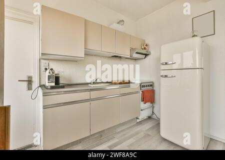 Cozy vintage kitchen interior with classic white refrigerator, beige cabinets, and tiled backsplash. Stock Photo