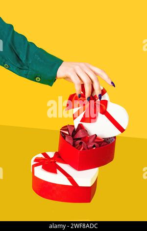 Anonymous hand lifting the lid off a heart shaped gift box revealing another heart box inside on a yellow background Stock Photo
