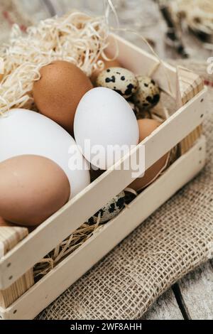Close-up view of a wooden basket filled with brown, white, and speckled quail eggs nestled in straw. Stock Photo