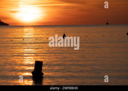 A sunset view of tranquil sea with distant fleet of small boats Stock Photo