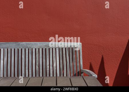 Wooden table and chair against red textured wall, Curacao Stock Photo