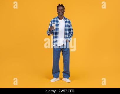 Handsome black man holding takeaway coffee in hand and smiling at camera Stock Photo