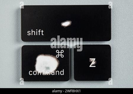 The command key, shift key and Z key are worn out due to frequent use and are removed from a keyboard with grey background Stock Photo