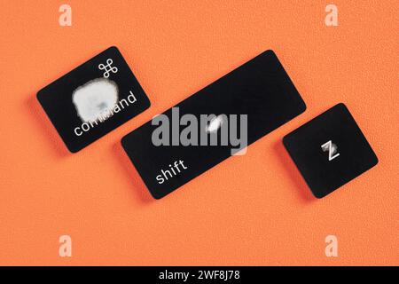 The command key, shift key and Z key are worn out due to frequent use and are removed from a keyboard with orange background Stock Photo