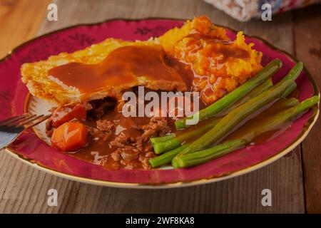 Minced beef and onion pie with green beans and mashed sweet potatoes and a rich gravy. Stock Photo