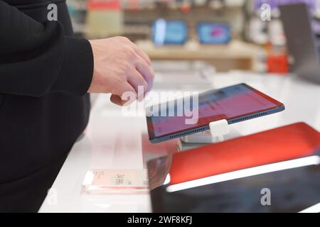 A white man uses a digital tablet in an electronics store. Stock Photo