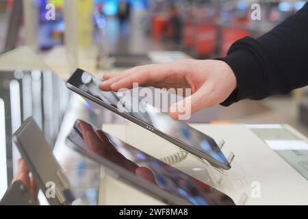 A white man uses a digital tablet in an electronics store. Stock Photo