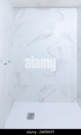 New shower under construction with white marble imitation tile, empty background. Home renovation concept Stock Photo