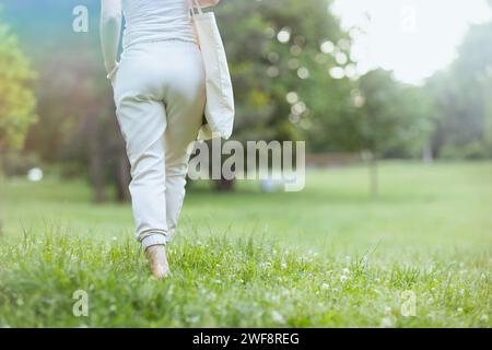 Summer time. Closeup on female in white shirt walking in the meadow in the city park. Stock Photo