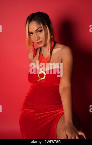 Stunning young woman confidently poses in red dress for a captivating photograph Stock Photo