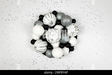 Christmas composition, fir tree decorations, white, silver and black baubles, silver stars confetti on white background. Stock Photo