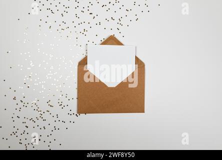 Christmas composition, kraft envelope, gold stars confetti on white background. Christmas, New Year, winter concept. Top view, flat lay, copy space. Stock Photo