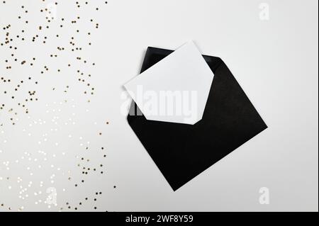 Christmas composition, black envelope, gold stars confetti on white background. Christmas, New Year, winter concept. Top view, flat lay, copy space. Stock Photo
