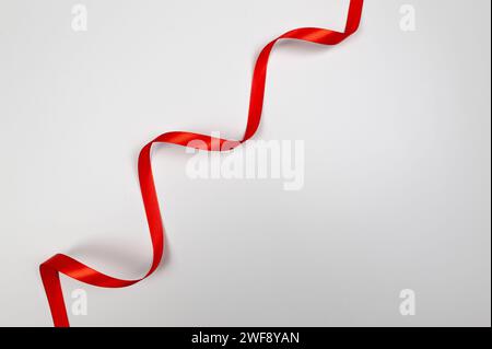 Top view of red ribbon on white background. Shiny rolled fabric, silk and satin material. Copy space. Stock Photo