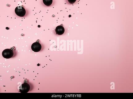 Christmas composition, black decorations, black baubles, silver stars confetti on pink background. Christmas, new year, winter concept. Stock Photo