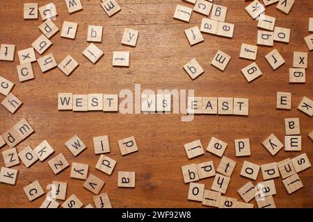 west versus east letters on wooden background Stock Photo