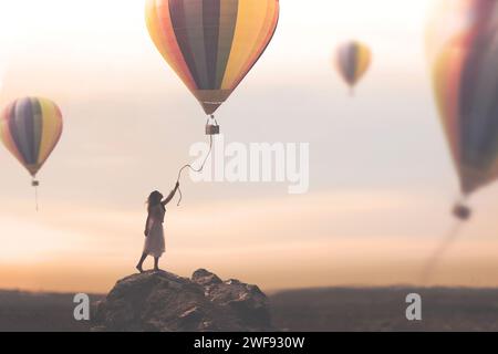 woman tries to catch the thread coming down from a hot air balloon that escapes free into the sky, concept of travel and adventure Stock Photo