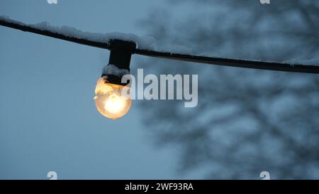 Snow-Covered Outdoor Light Bulb Illuminated in Winter Evening, Swiss winter Stock Photo