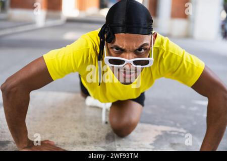 An athletic man in vibrant attire striking an urban dance pose on a city street. Stock Photo