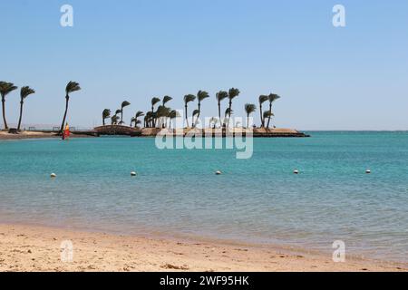 Beautiful place for privacy. Sunset over island in sea. Bright sun during dawn over the sea. Island with palm trees and benches in ocean. Summer vacat Stock Photo