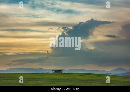 a lone home upon a hill under a cloudy sun set sky Stock Photo