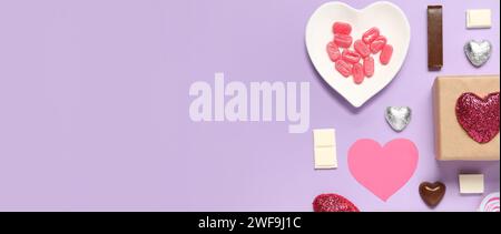 Different tasty sweets and gift box on lilac background with space for text. Valentine's Day celebration Stock Photo