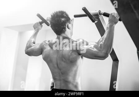 Young strong man bodybuilder doing pulling up on the bar in a modern gym Stock Photo