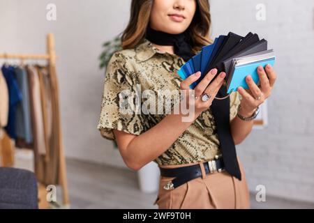 cropped view of professional designer choosing color from samples in fashion studio Stock Photo