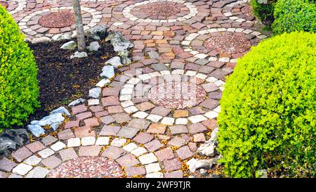Circular paving of a path near the house and in the garden. An original variant of paving stones for garden paths. Red and white granite walkway laid Stock Photo