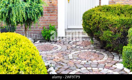 Original garden path with circular paving close-up. Pathway from brick paving stones made of red and white granite. Creative design ideas for a walkwa Stock Photo