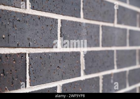 Masonry brick wall sloping away to the right. Dark gray stones and white joints. Narrow depth of field Stock Photo