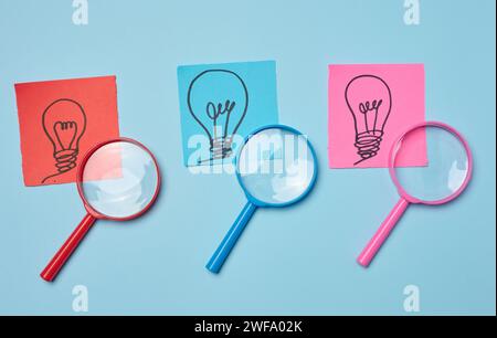 Drawn light bulbs on sheets of paper and a plastic magnifying glass, the concept of searching for new ideas Stock Photo
