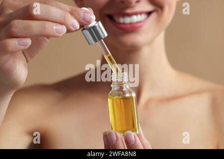 Woman with cosmetic serum in her hands on beige background, closeup Stock Photo