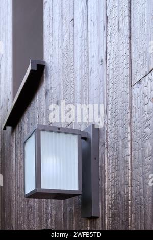 Modern external lamp on burned wood wall Stock Photo