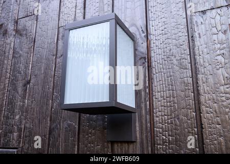 Modern external lamp on burned wood wall Stock Photo