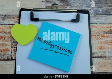 Concept of MicroAggressions write on sticky notes isolated on Wooden Table. Stock Photo