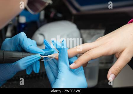 Using an electric file for precise edge nail shaping in a manicure. Stock Photo
