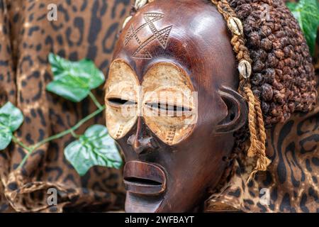 Wooden tribal African mask from Uganda, for family or personal protection, made of local wood, ropes and seashells as hair decoration Stock Photo