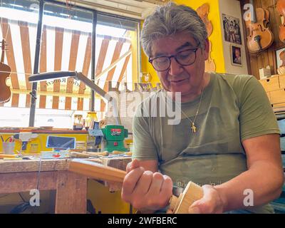 master luthier violin maker working on violin scroll in his workshop in Cremona Italy Stock Photo