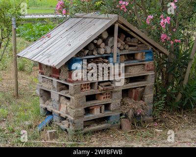 Insect or bee hotel in a summer garden. An insect hotel is a man-made structure to house insects of various shapes, sizes, and materials Stock Photo