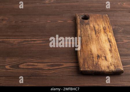 Empty rectangular wooden cutting board on brown wooden background. Side view, copy space. Stock Photo