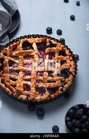 Red fruit and blueberry pie presented on a light blue background. Stock Photo