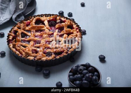 Red fruit and blueberry pie presented on a light blue background. Stock Photo