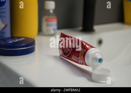 Colgate toothpaste opened near other body products on a bathroom counter Stock Photo