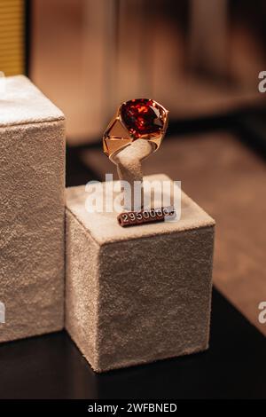 A gold ring with a huge ruby on the counter in a jewelry boutique. Expensive accessories for gifts for women Stock Photo