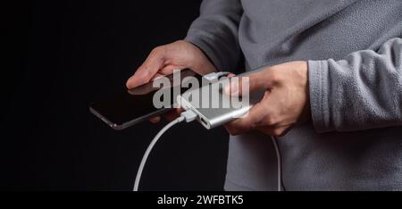 The men hand hold the phone and charger, powerbank and smart phone is connecting, energy. Stock Photo